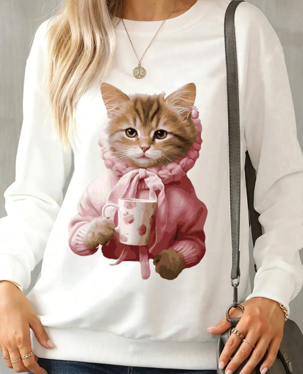 White sweatshirt with a cat holding a mug design on a gray background