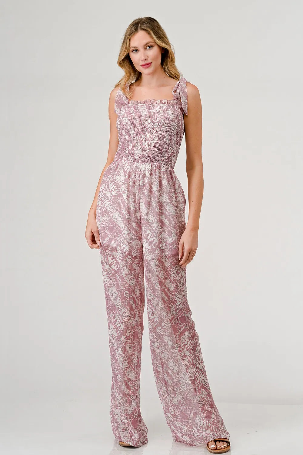 Woman wearing a pink floral jumpsuit on a white background