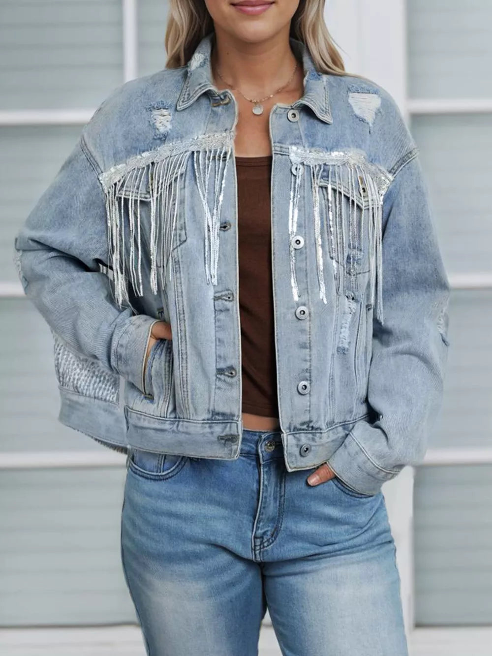 Person wearing a light blue denim jacket with fringe details and high-waisted jeans.