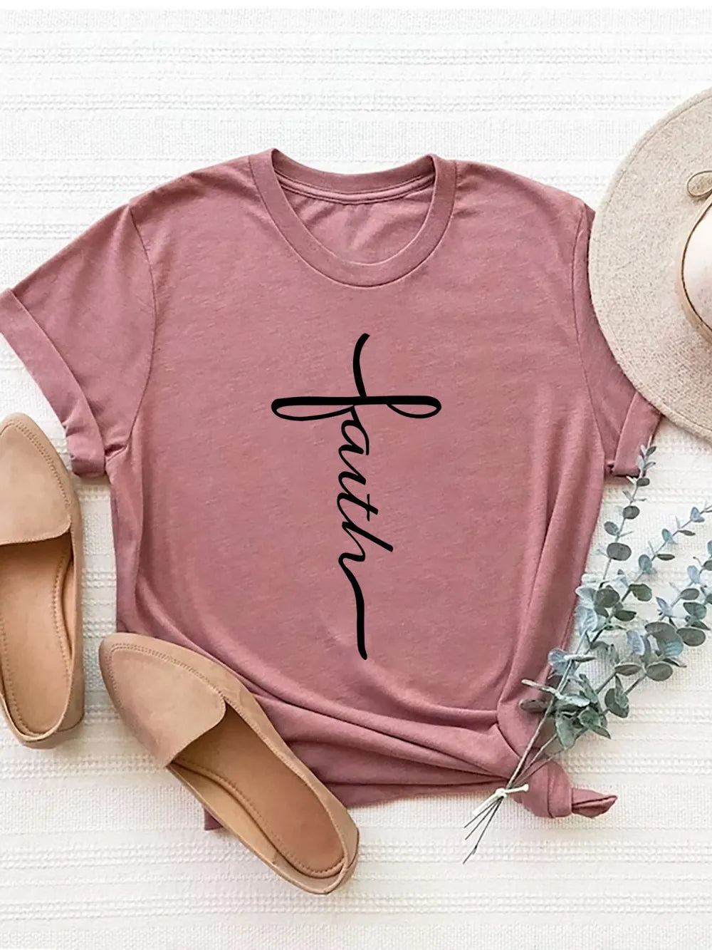 Pink t-shirt with 'faith' text, beige shoes, and a hat on a light background