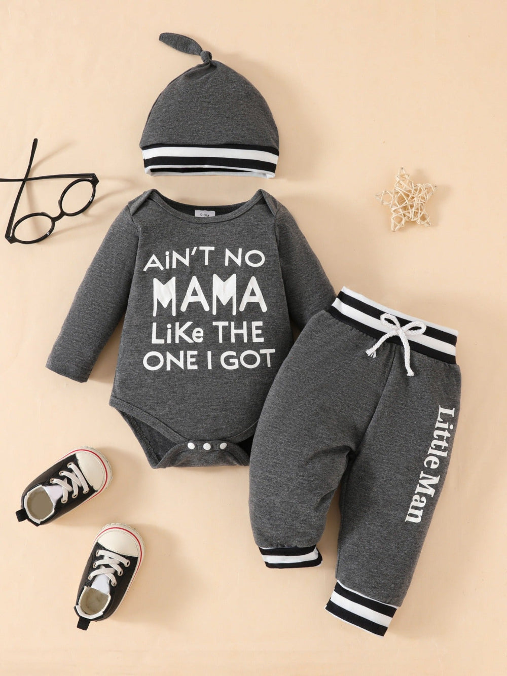 Baby outfit set with 'Ain't no mama like the one I got' onesie, pants, and hat on a beige background.