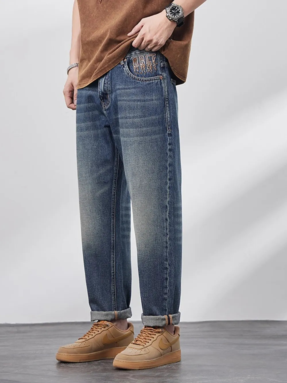 Person wearing blue jeans and brown shoes on a plain background